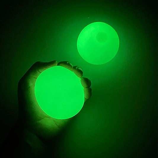 Beckett Sticky Glow Balls in various sizes glowing in the dark on a dark background, perfect for sensory play and entertainment.